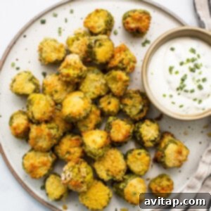 A plate of golden-brown air-fried pickles with a creamy dipping sauce on the side.