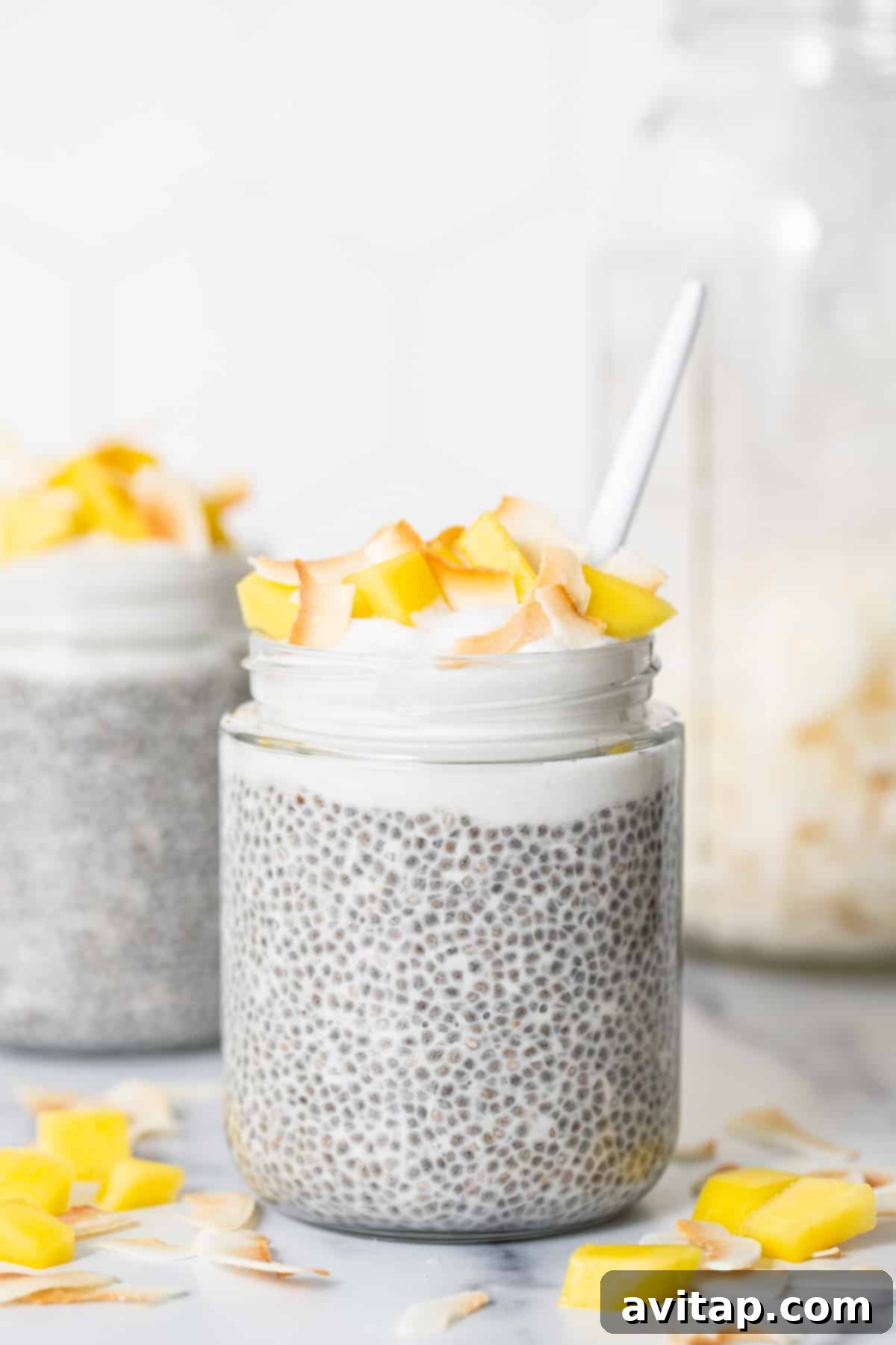 Two jars of protein coconut cream pie chia pudding on a marble counter, ready for enjoyment.