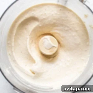 A food processor blending a white, creamy substance.