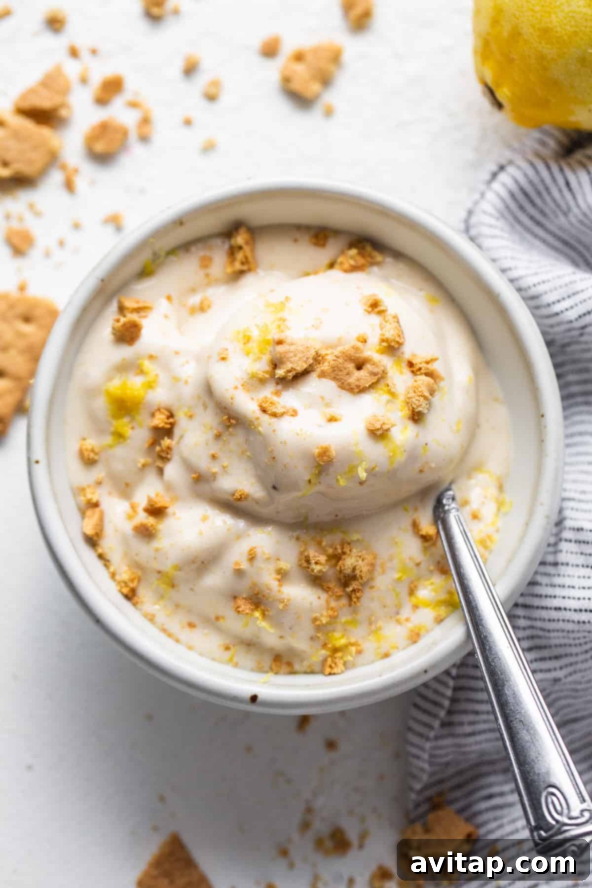 Zesty Lemon Cheesecake Nice Cream 7 A bowl of creamy lemon cheesecake nice cream with a spoon, ready to be enjoyed.