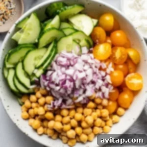 Chickpea and cucumber salad being tossed with dressing in a bowl.