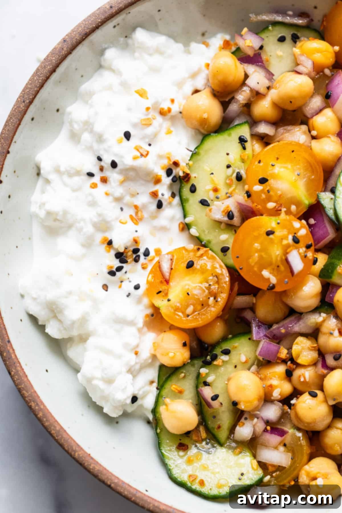 A bowl of fresh chickpea salad with creamy cottage cheese and crisp cucumbers, artfully arranged for a delightful meal.