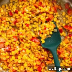 Corn in a pan with a green spatula.
