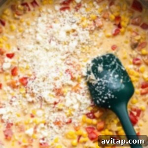 Corn chowder in a pan with a green spatula.