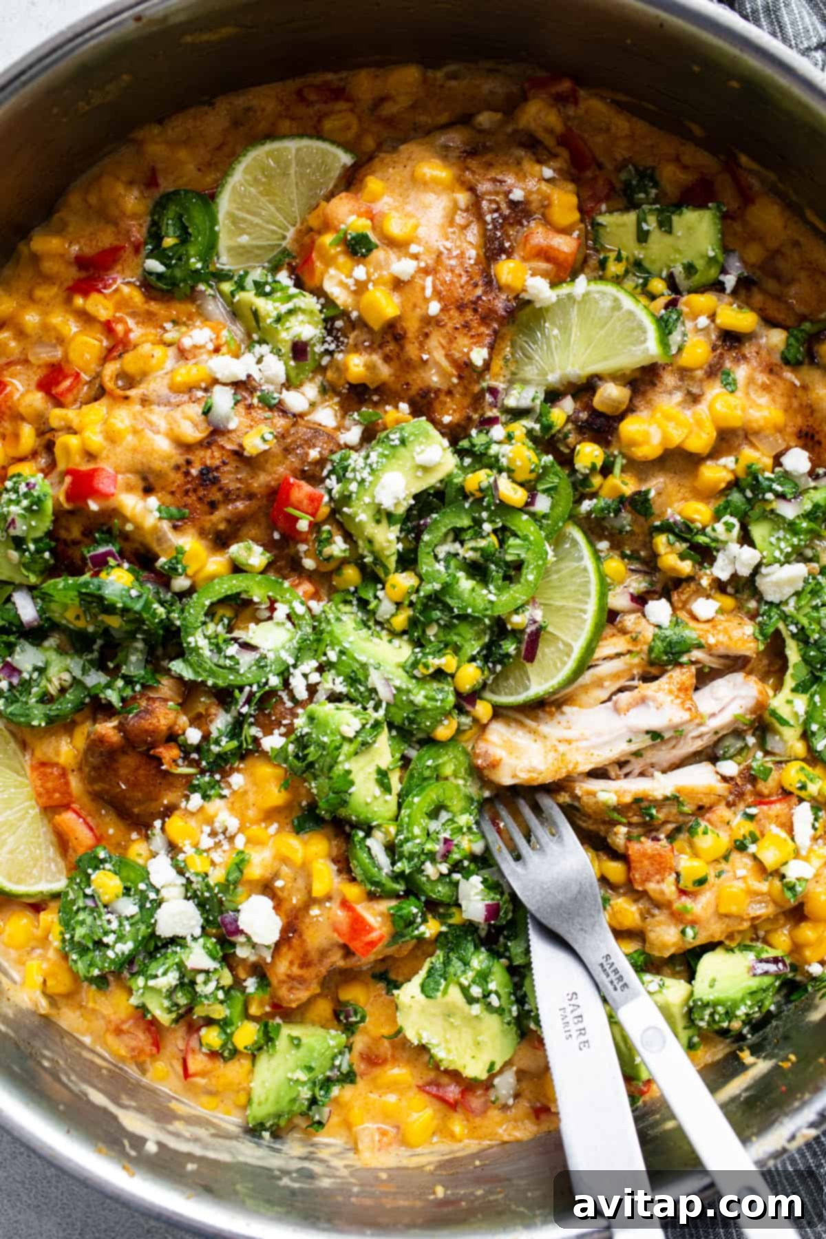 A pan with chicken, corn and vegetables in it.