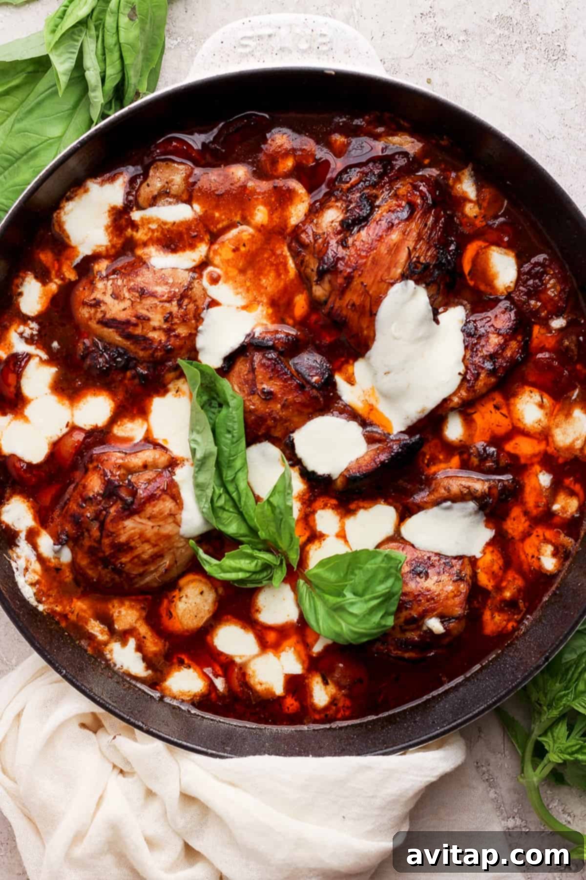A skillet with chicken in a rich balsamic sauce, garnished with fresh basil leaves, ready to be served.