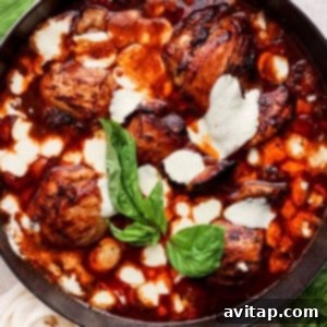 A skillet with finished balsamic chicken in a sauce, topped with vibrant green basil leaves.