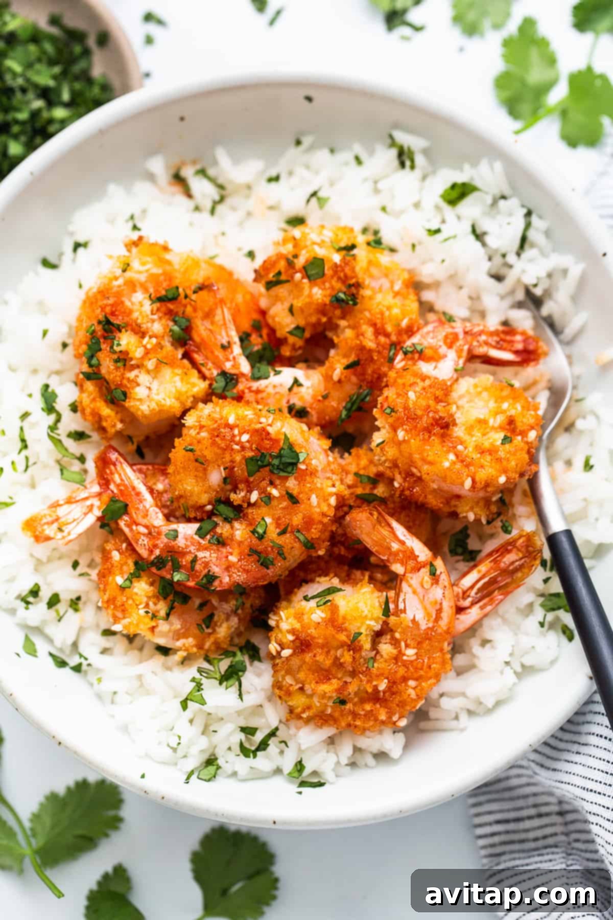 Crispy Air Fryer Firecracker Shrimp 2 A bowl of fluffy white rice topped generously with vibrant, crispy firecracker shrimp and a garnish of fresh herbs.