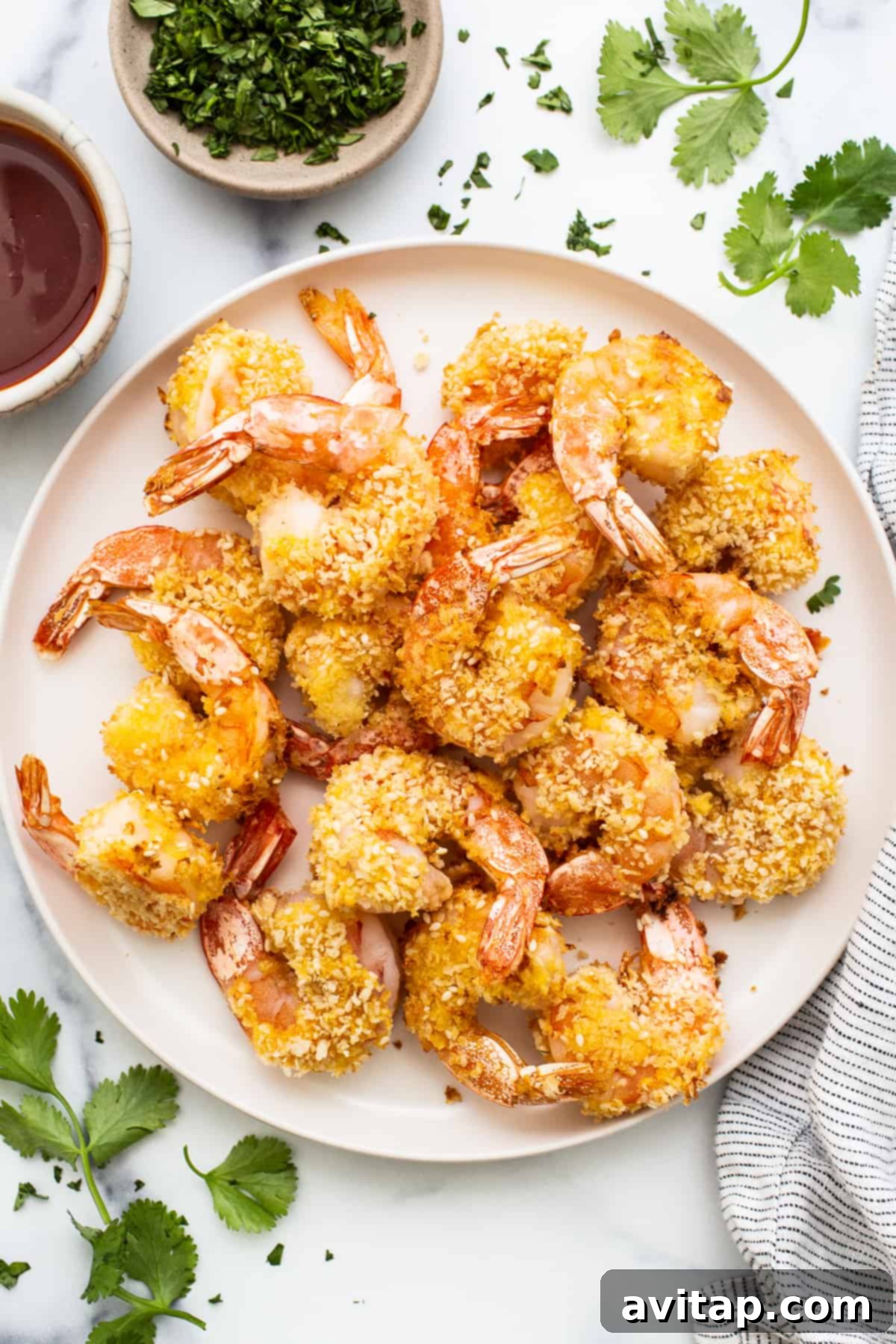 Fried shrimp on a white plate with fresh herbs and a drizzle of firecracker sauce.