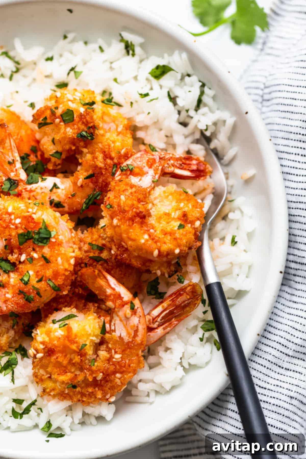 Crispy Air Fryer Firecracker Shrimp 6 A delectable close-up of a bowl filled with succulent shrimp and rice, with a fork poised for a bite.