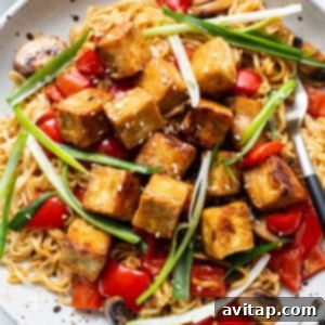 Asian tofu noodles with mushrooms and tomatoes on a plate, ready to be garnished.