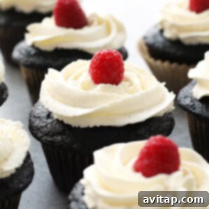 Healthier chocolate cupcakes topped with a fresh raspberry and honey whipped cream frosting.
