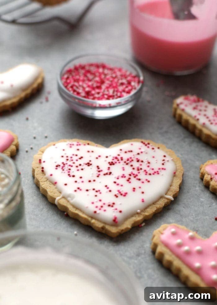 A spread of healthy, frosted almond flour sugar cookies Healthy sugar cookies with pink frosting on a counter