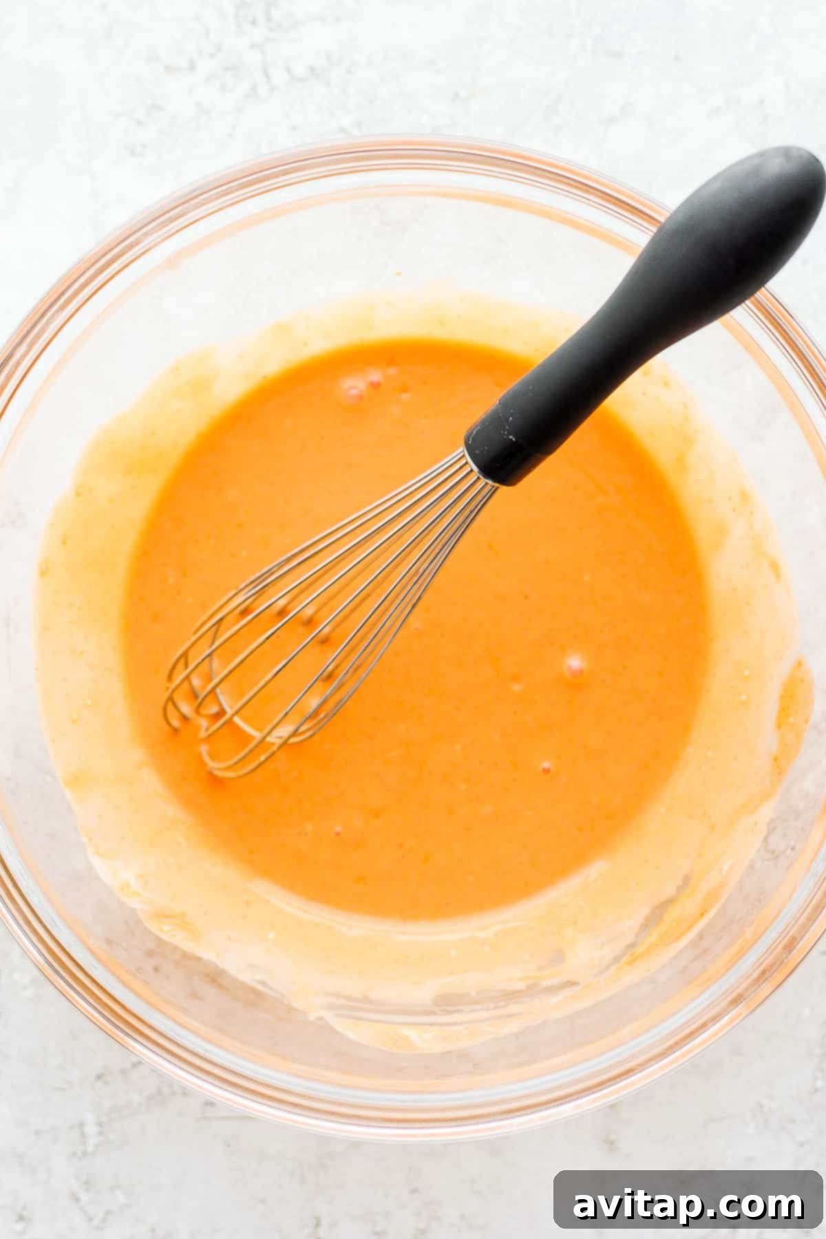 A bowl filled with vibrant red buffalo sauce, signaling the exciting flavors to come in a chicken wrap recipe