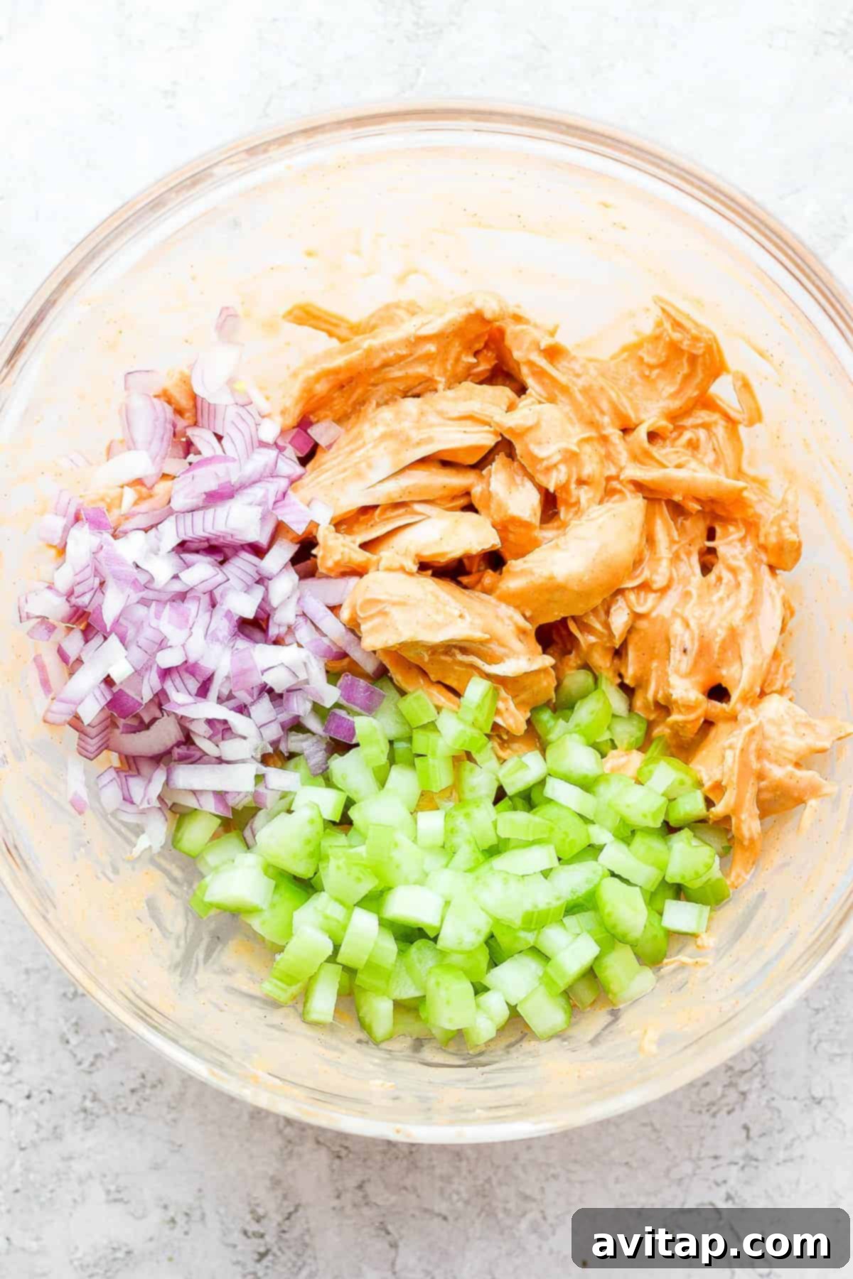 A bowl of flavorful buffalo chicken mixture with finely diced vegetables, ready to be wrapped