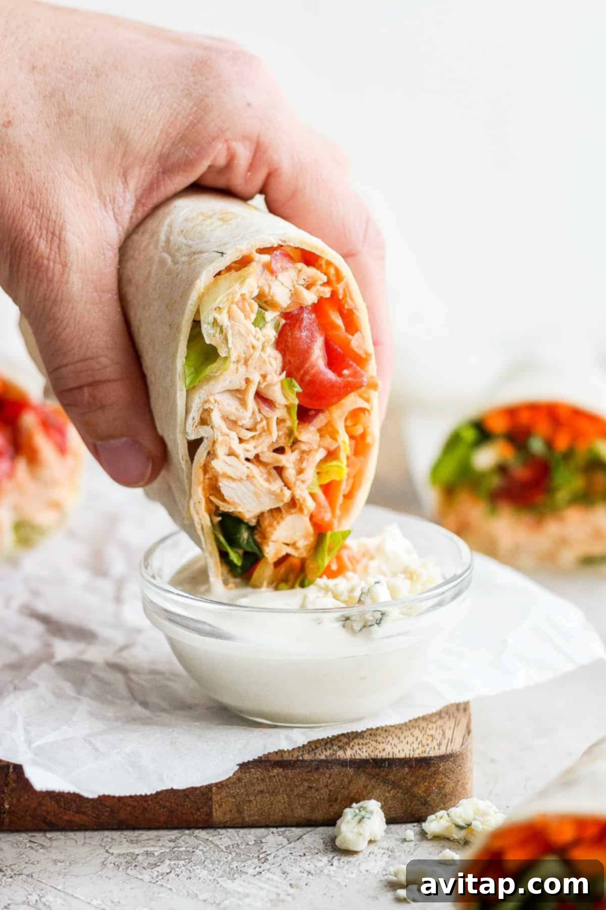 A vibrant Buffalo Chicken Wrap with fresh ingredients spilling out slightly, showcasing its deliciousness