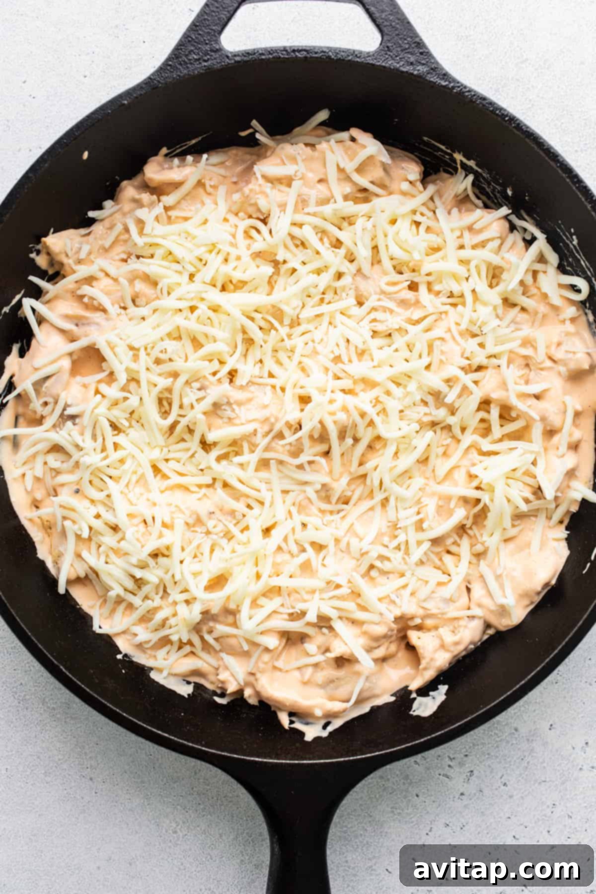 A perfectly baked, golden-brown, and bubbly whipped cottage cheese buffalo chicken dip in a cast iron skillet.