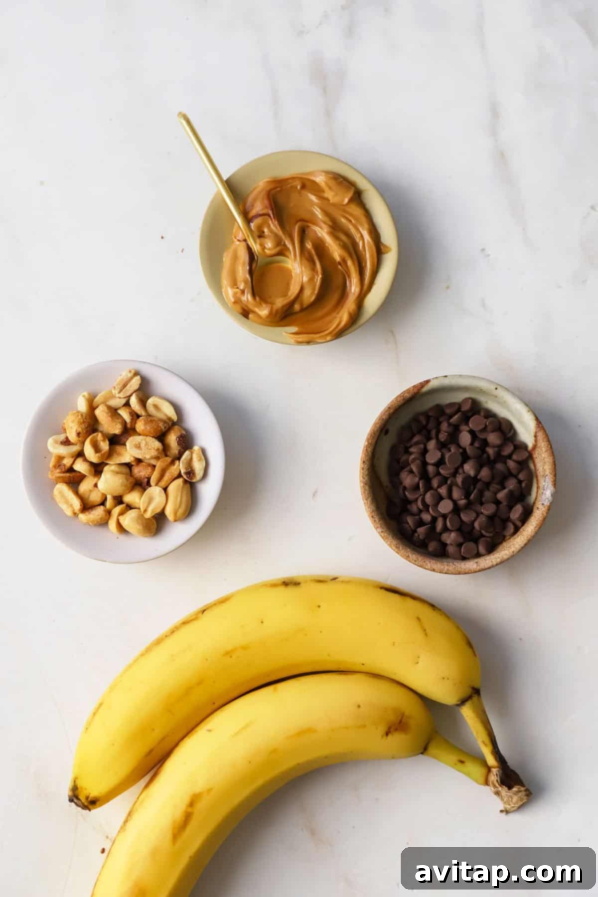 Ingredients for Air Fryer Banana Split: Bananas, peanut butter, mini chocolate chips, and chopped peanuts.