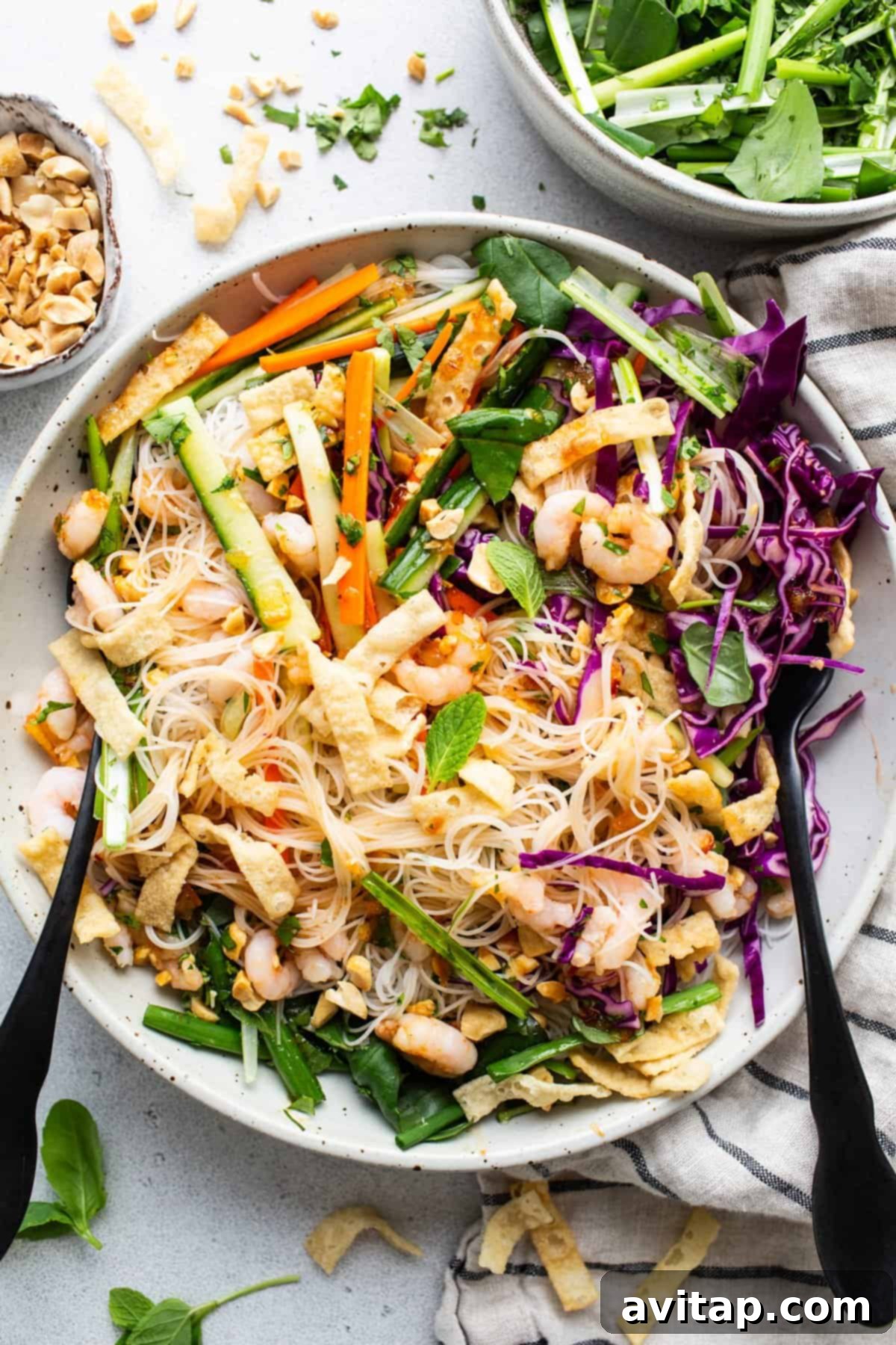 A bowl of Asian noodle salad with peanuts and vegetables.