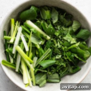 Fresh herbs in a bowl on a white surface.