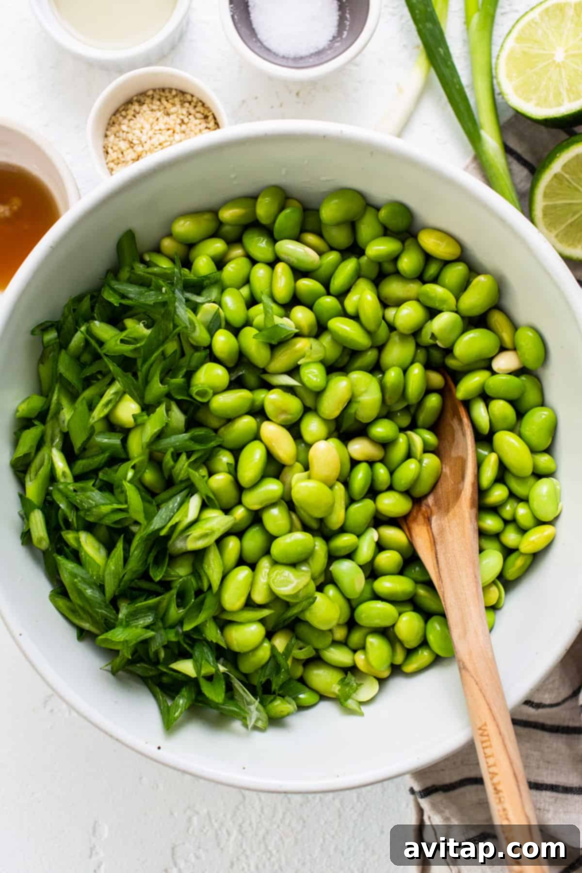 a white bowl filled with green beans and a wooden spoon.