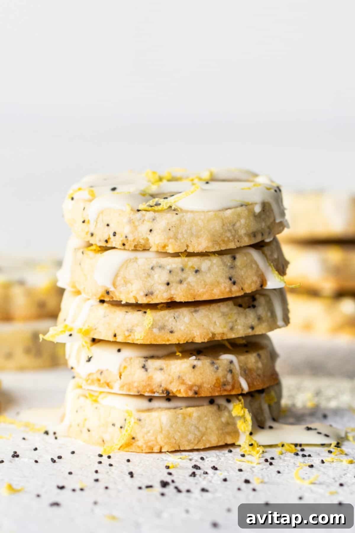 Lemon Poppy Seed Shortbread 2 A stack of golden shortbread cookies with white chocolate drizzle and poppy seeds.