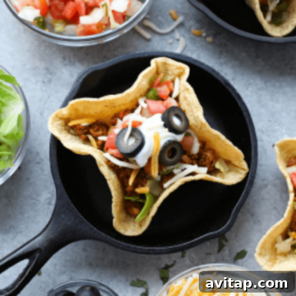 A group of beautifully assembled mini taco cups in a black skillet on a table, ready for serving.