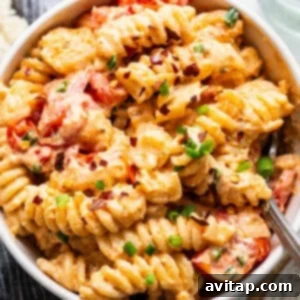Creamy Roasted Garlic Boursin Bake 3 A bowl of creamy pasta with tomato pieces and sprinkled with herbs.