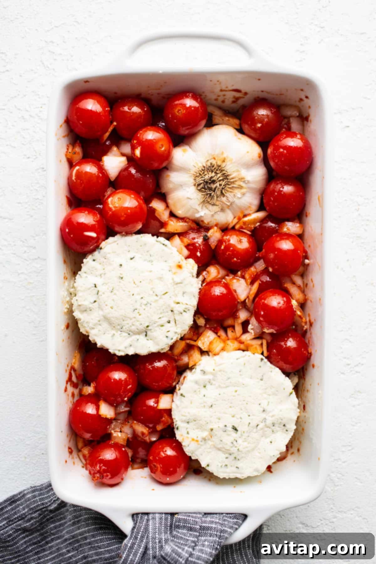 Creamy Roasted Garlic Boursin Bake 4 A white baking dish filled with roasted tomatoes and Boursin cheese, ready to be mashed.