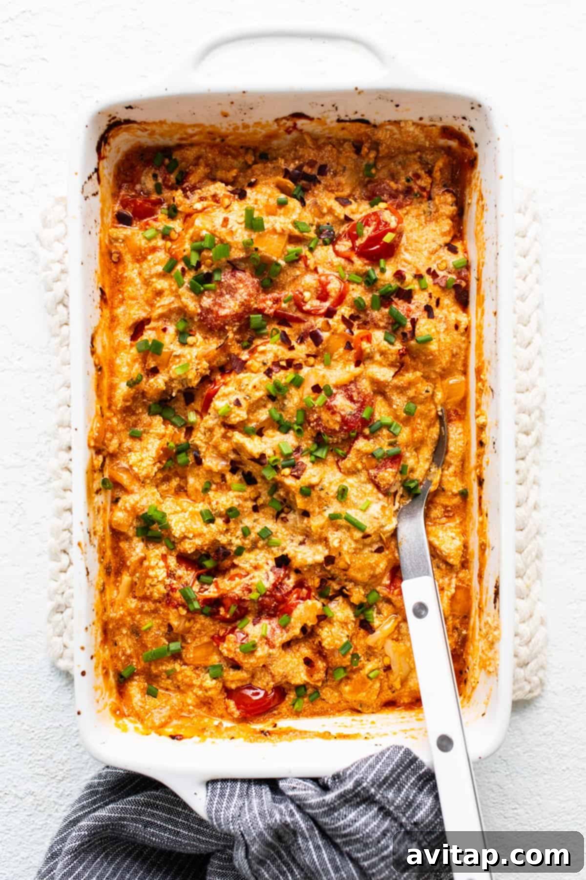Creamy Roasted Garlic Boursin Bake 7 A casserole dish filled with baked Boursin dip, with a fork poised to scoop, highlighting its creamy texture.