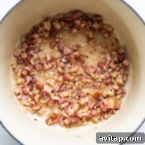 Easy Weeknight Carbonara 10 Pancetta cooking in a blue pot on a white surface.