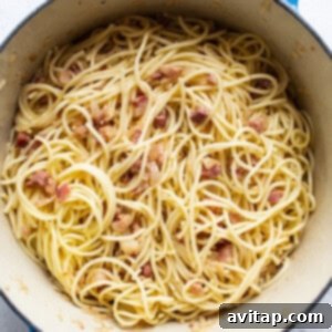 Easy Weeknight Carbonara 11 A pan full of spaghetti with bacon and cooked onions.