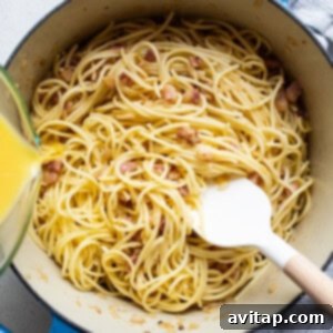 Easy Weeknight Carbonara 12 A pot of spaghetti with bacon and egg mixture being poured over it.
