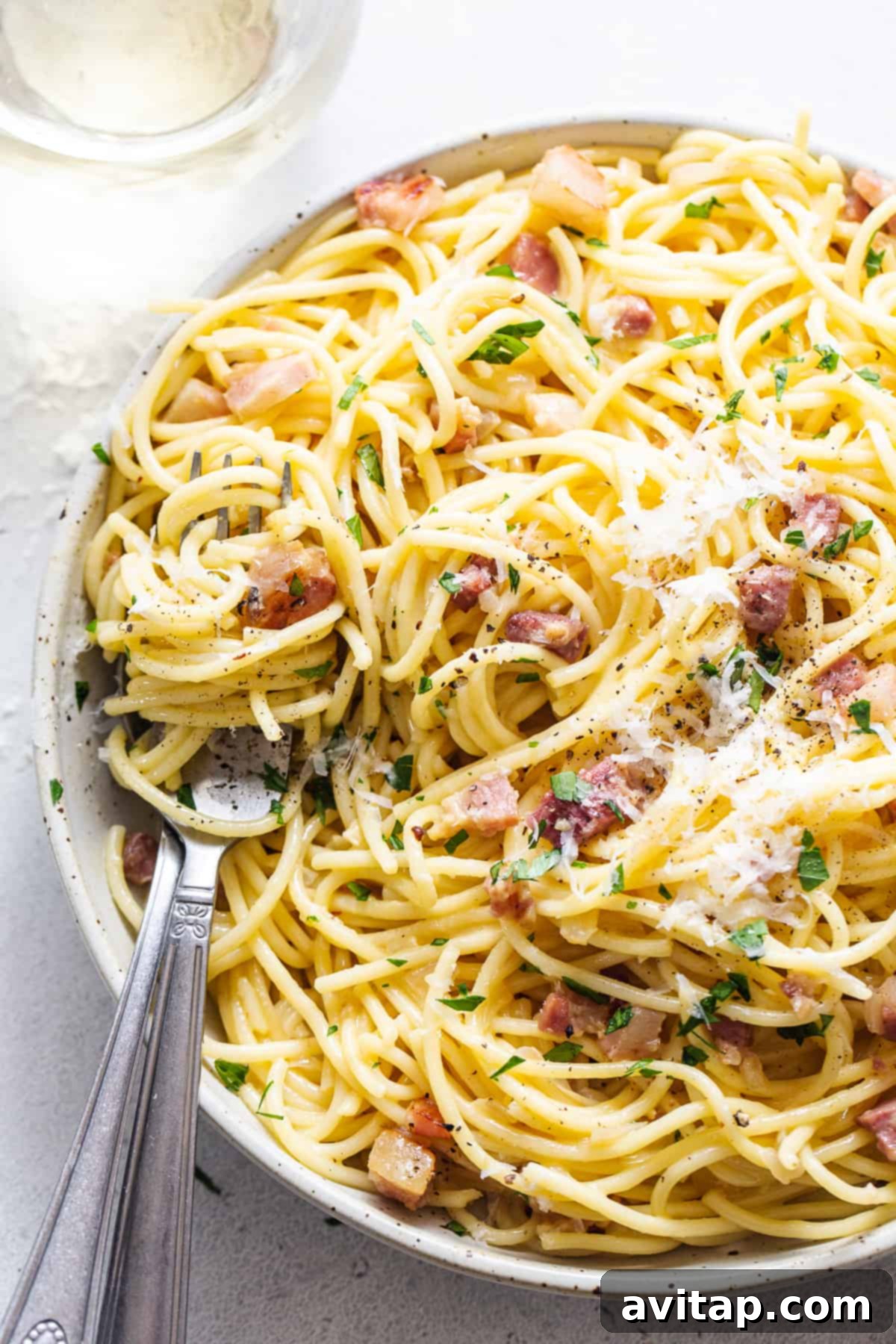 Easy Weeknight Carbonara 7 A serving of spaghetti carbonara in a white bowl, garnished with fresh parsley.