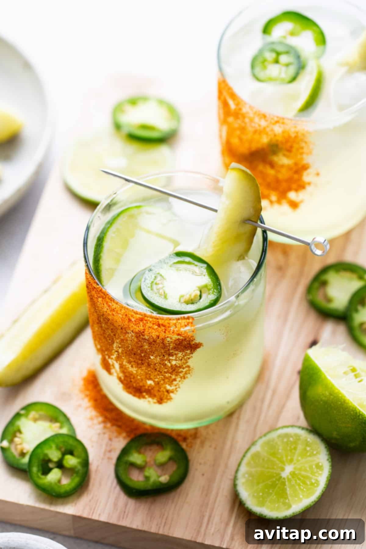 A glass of drink with a pickle and lime slices.