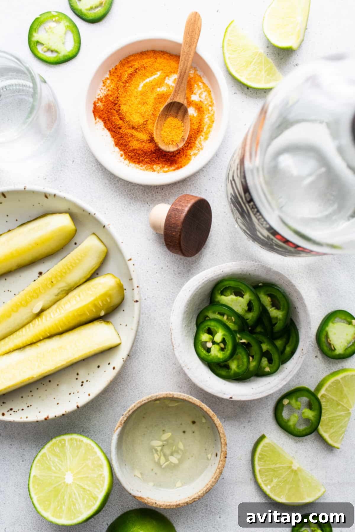 A plate with cucumbers, limes and a bottle of tequila.