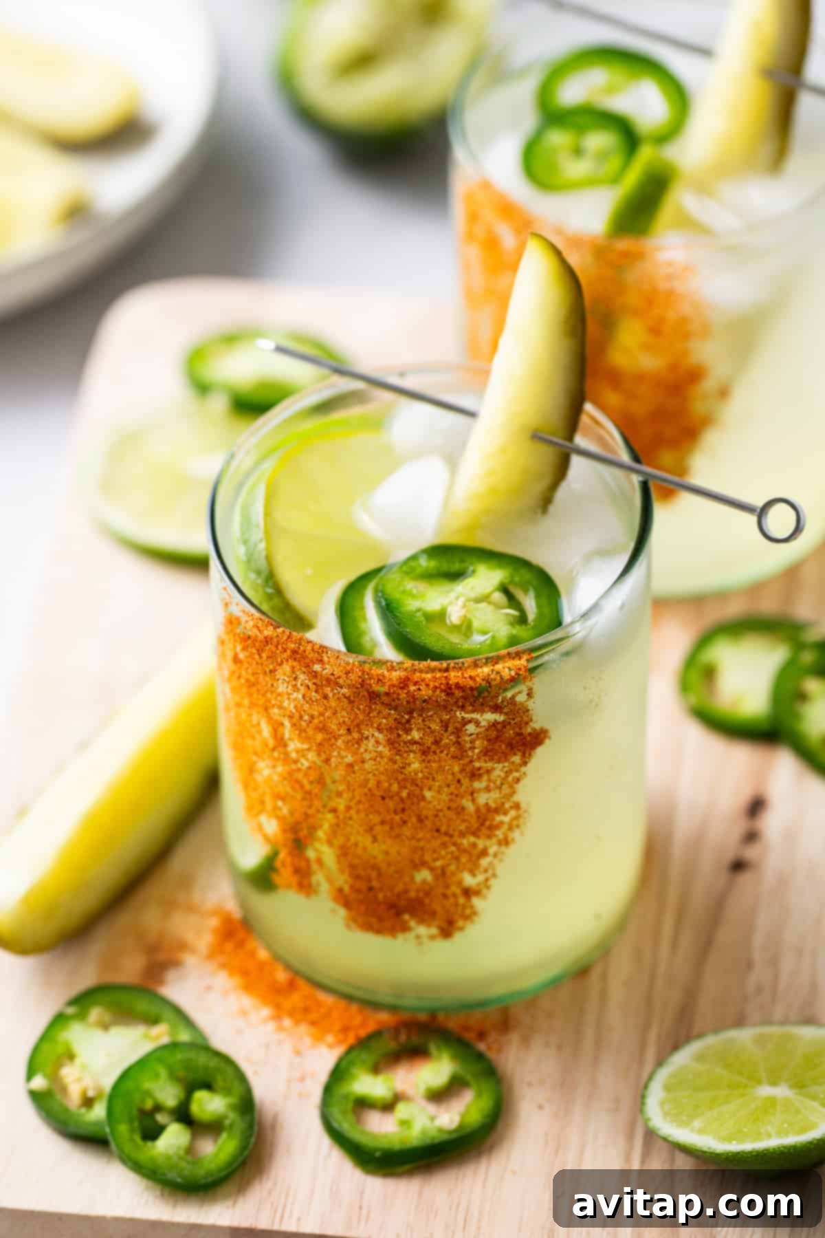 Two glasses of jalapeno margarita with lime and jalapeno.