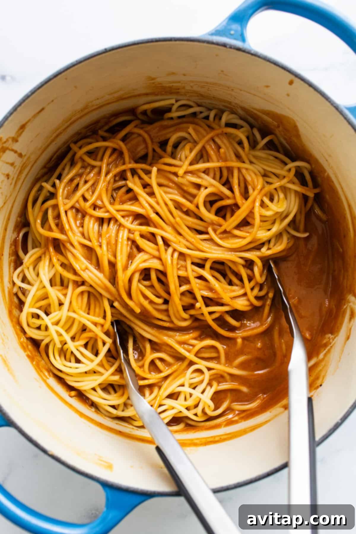 Spaghetti pasta cooking in a blue pot, with two forks resting on the side.