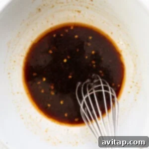 A bowl containing the whisked sauce ingredients, a blend of soy sauce, chili, ginger, and honey, ready to flavor the ramen dish.
