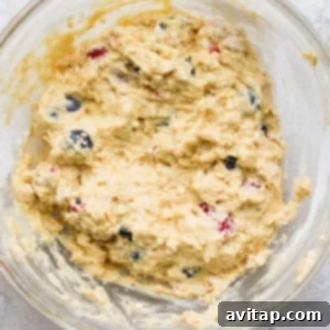 A bowl of muffin batter, thick and slightly lumpy, with blueberries folded in, ready for baking.