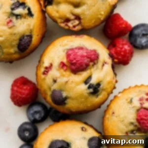 A charming close-up of a stack of Greek Yogurt Berry Muffins, garnished with fresh berries.