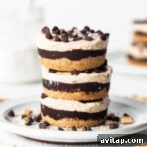 A stack of delicious peanut butter chocolate cheesecake cups on a white plate, garnished with chocolate shavings and chopped peanuts.