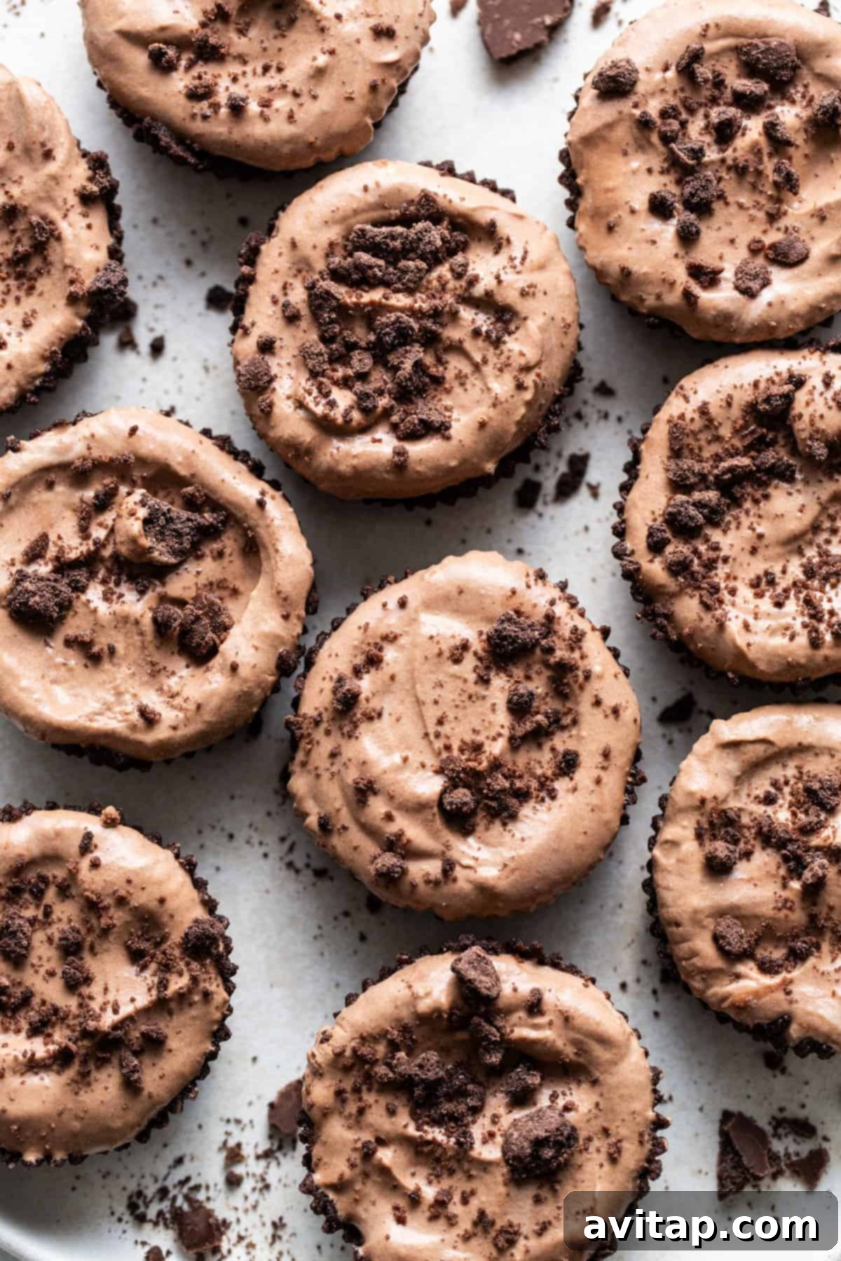 Individual chocolate mousse cups, elegantly topped with chocolate shavings and a hint of mint, presented on a pristine white serving plate.