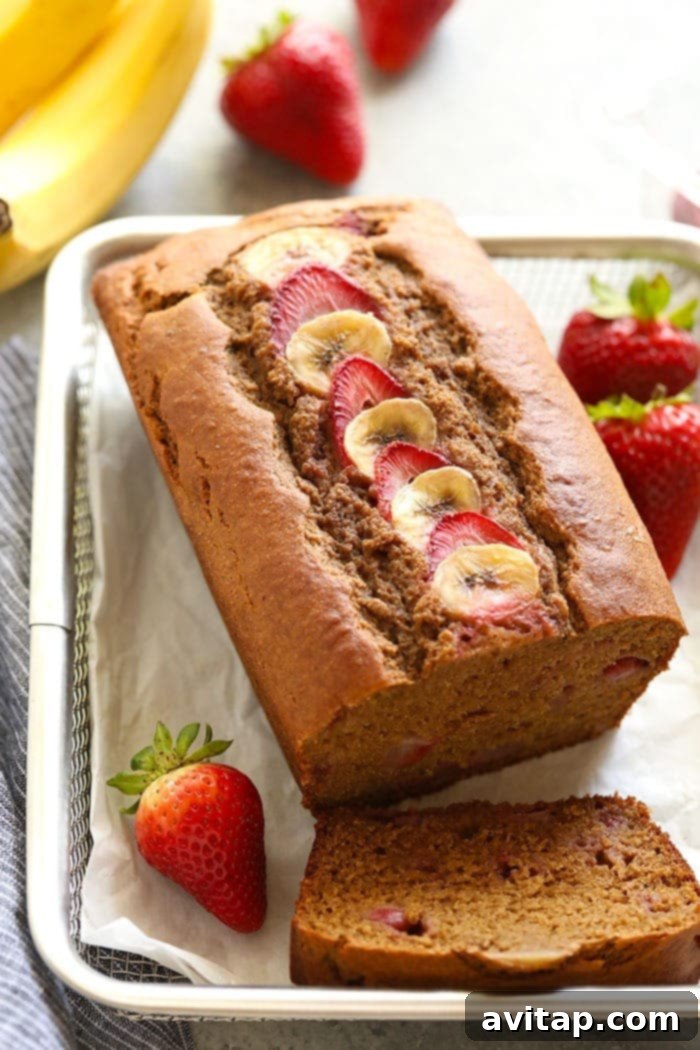 Effortless Strawberry Banana Bread 2 A slice of moist strawberry banana bread with fresh strawberries and banana slices on top.