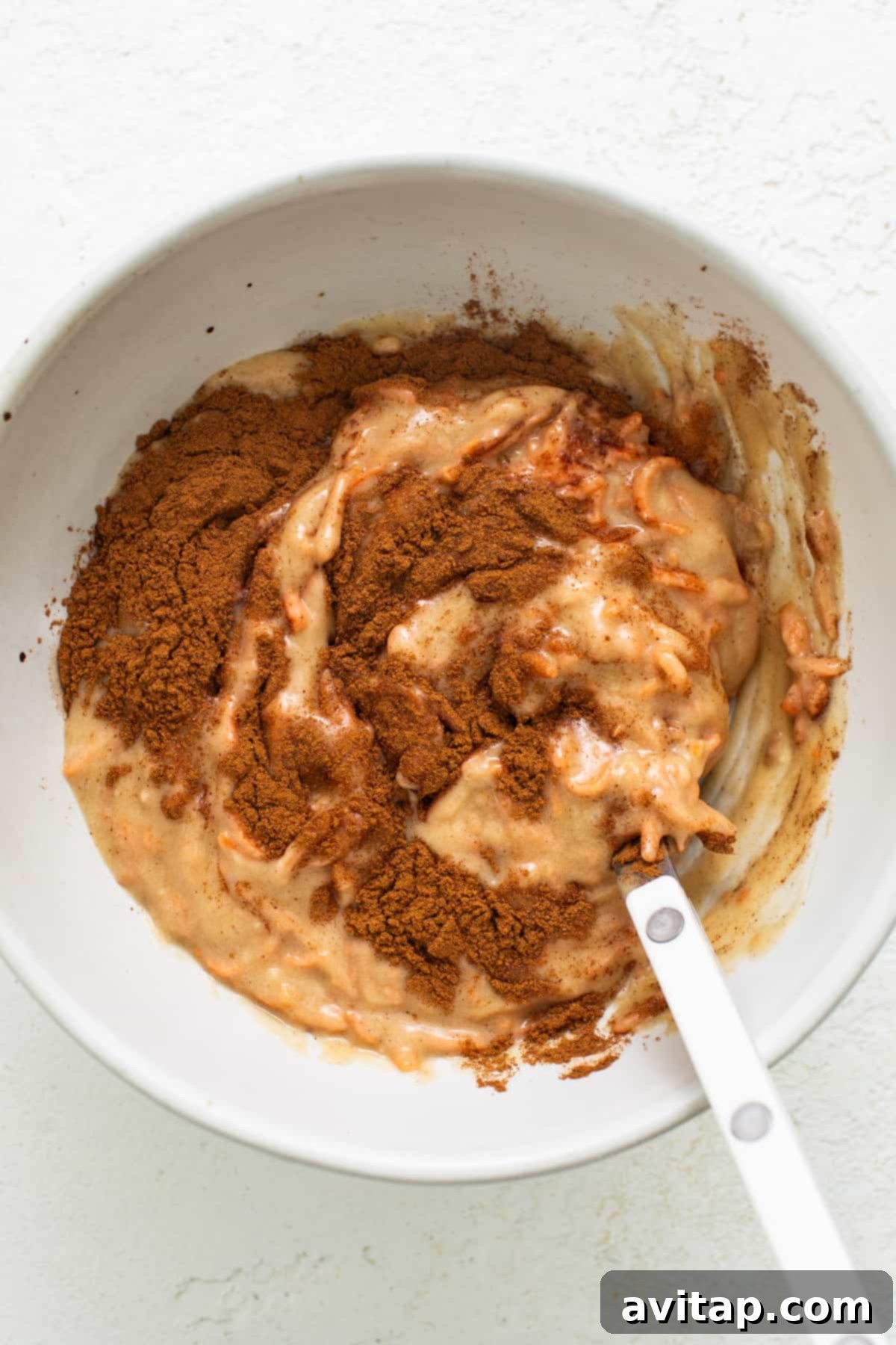 A pristine white mixing bowl with a spoon, ready for baking preparations.