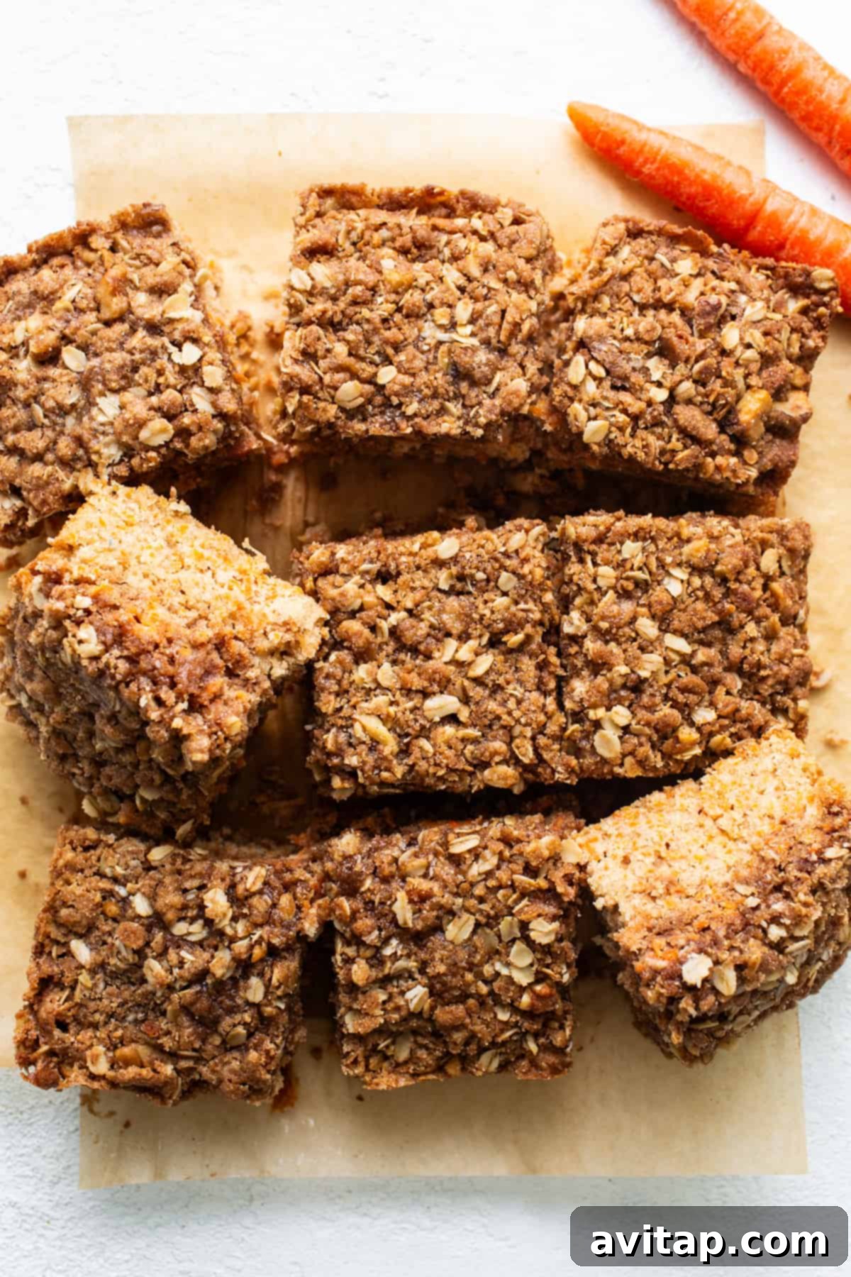 Slices of freshly baked Carrot Cake Coffee Cake adorned with oats and carrots on a rustic cutting board.