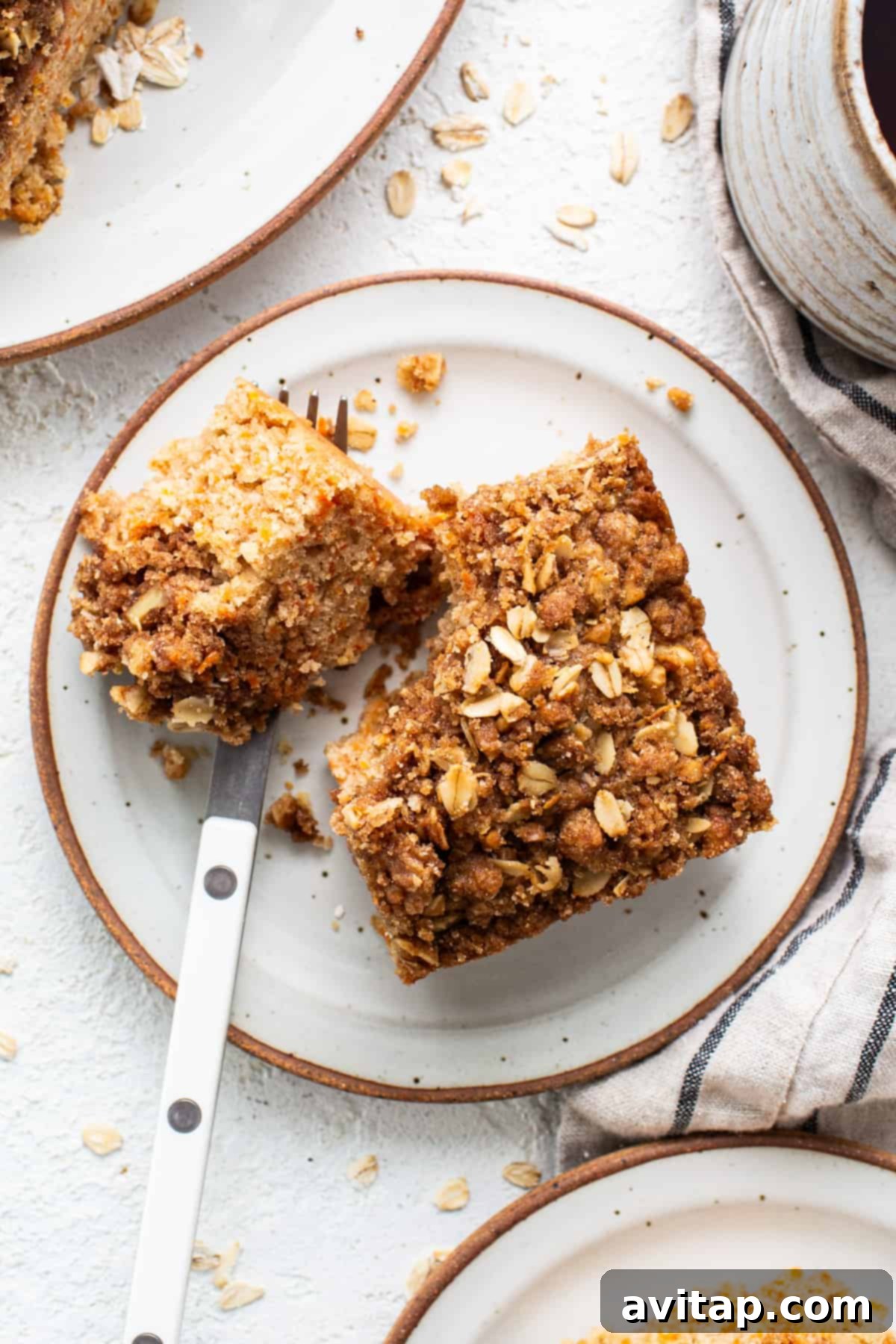 A delectable slice of Carrot Cake Coffee Cake on a plate, perfectly paired with a steaming cup of coffee.