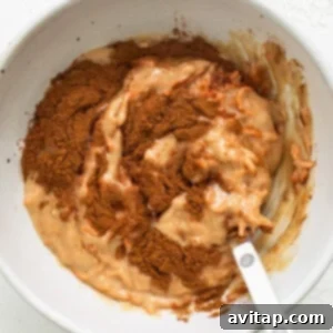 A white bowl with a spoon mixing cake batter.