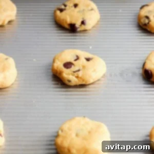 Unbaked chocolate chip cookies arranged neatly on a baking sheet, ready for the oven.