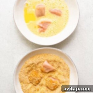 A hand dredging a piece of chicken into a bowl of dry coating mixture.
